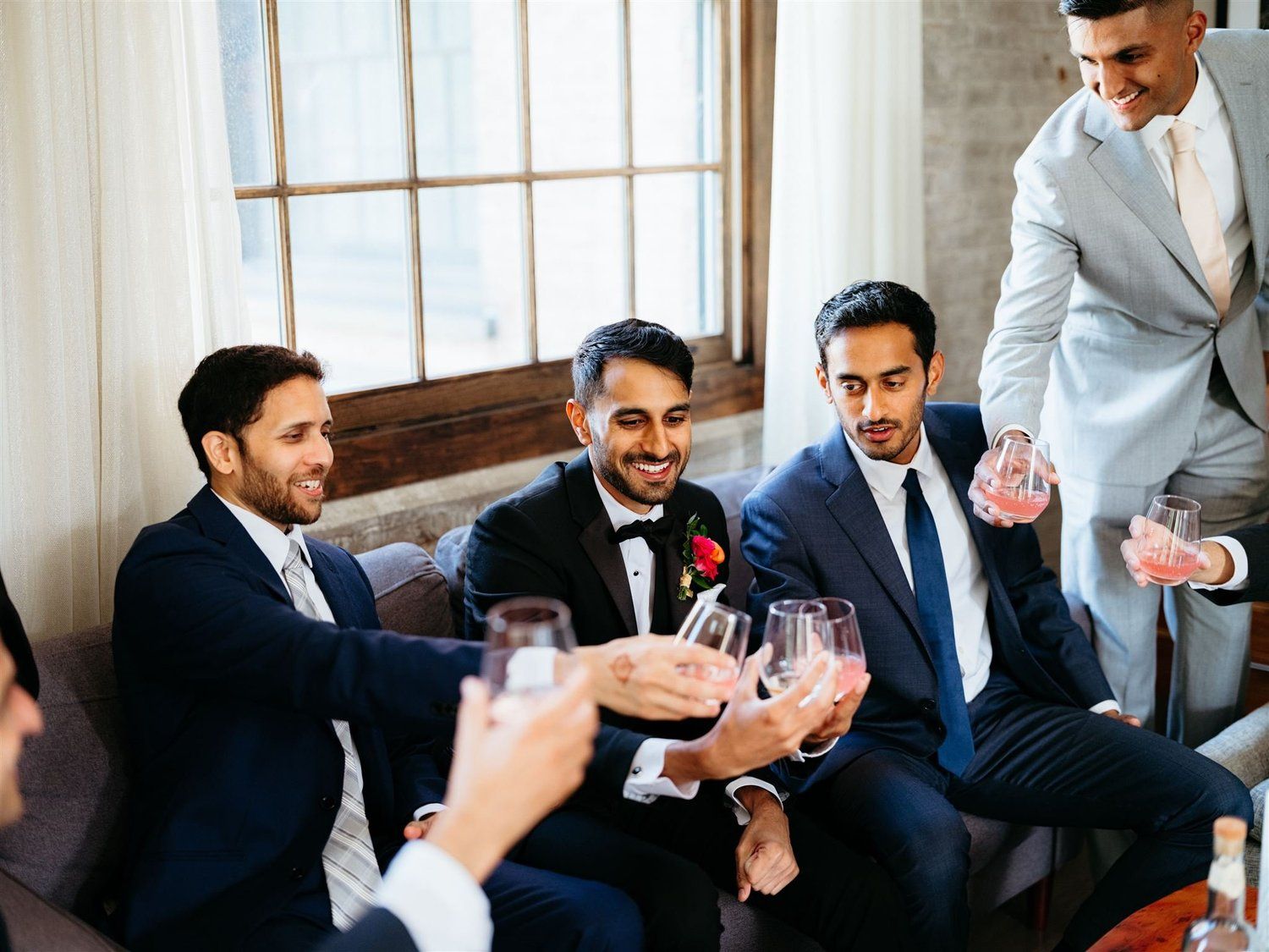 Friends in suits raising a toast, freshly groomed